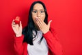 Beautiful hispanic woman with nose piercing holding engagement ring for proposal covering mouth with hand, shocked and afraid for Royalty Free Stock Photo