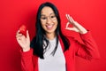 Beautiful hispanic woman with nose piercing holding engagement ring for proposal doing ok sign with fingers, smiling friendly Royalty Free Stock Photo