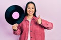 Beautiful hispanic woman with nose piercing holding vinyl disc smiling happy and positive, thumb up doing excellent and approval Royalty Free Stock Photo