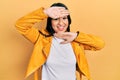 Beautiful hispanic woman with nose piercing wearing yellow leather jacket smiling cheerful playing peek a boo with hands showing Royalty Free Stock Photo