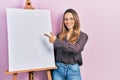 Beautiful hispanic woman pointing to painter easel stand smiling with a happy and cool smile on face Royalty Free Stock Photo