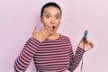 Beautiful hispanic woman with short hair holding usb charger adapter for the car covering mouth with hand, shocked and afraid for Royalty Free Stock Photo