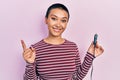 Beautiful hispanic woman with short hair holding usb charger adapter for the car smiling happy pointing with hand and finger to Royalty Free Stock Photo