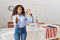 Beautiful hispanic woman standing by at political campaign by voting ballot doing money gesture with hands, asking for salary