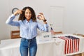 Beautiful hispanic woman standing by at political campaign by voting ballot smiling pointing to head with one finger, great idea