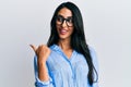Beautiful hispanic woman wearing business clothes and glasses pointing thumb up to the side smiling happy with open mouth Royalty Free Stock Photo
