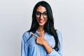 Beautiful hispanic woman wearing business clothes and glasses smiling cheerful pointing with hand and finger up to the side Royalty Free Stock Photo
