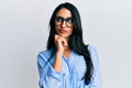 Beautiful hispanic woman wearing business clothes and glasses thinking concentrated about doubt with finger on chin and looking up Royalty Free Stock Photo