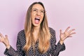 Beautiful hispanic woman wearing casual clothes and glasses crazy and mad shouting and yelling with aggressive expression and arms Royalty Free Stock Photo