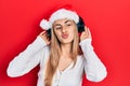 Beautiful hispanic woman wearing christmas hat and headphones looking at the camera blowing a kiss being lovely and sexy Royalty Free Stock Photo