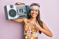 Beautiful hispanic woman wearing hippie style holding boom box smiling happy pointing with hand and finger Royalty Free Stock Photo
