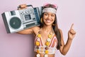 Beautiful hispanic woman wearing hippie style holding boom box smiling happy pointing with hand and finger to the side Royalty Free Stock Photo