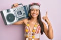 Beautiful hispanic woman wearing hippie style holding boom box smiling with an idea or question pointing finger with happy face, Royalty Free Stock Photo