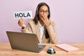 Beautiful hispanic woman wearing operator headset holding hola greenting covering mouth with hand, shocked and afraid for mistake