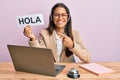 Beautiful hispanic woman wearing operator headset holding hola greenting smiling happy pointing with hand and finger
