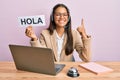 Beautiful hispanic woman wearing operator headset holding hola greenting smiling with an idea or question pointing finger with