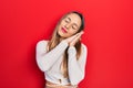 Beautiful hispanic woman wearing red diadem sleeping tired dreaming and posing with hands together while smiling with closed eyes Royalty Free Stock Photo