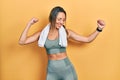 Beautiful hispanic woman wearing sportswear and towel dancing happy and cheerful, smiling moving casual and confident listening to Royalty Free Stock Photo