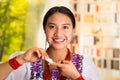 Beautiful hispanic woman wearing white blouse with colorful embroidery, applying cream onto face using finger during Royalty Free Stock Photo