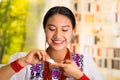 Beautiful hispanic woman wearing white blouse with colorful embroidery, applying cream onto face using finger during Royalty Free Stock Photo