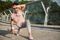 Beautiful Hispanic woman wiping her forehead from a sweat with a white terry wristband and looking aside sitting on a squat Royalty Free Stock Photo