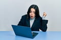 Beautiful hispanic woman working at the office with laptop scared and amazed with open mouth for surprise, disbelief face Royalty Free Stock Photo