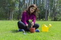 Beautiful Hispanic young woman placing a small plant inside a pot in her home garden Royalty Free Stock Photo