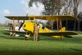 A beautiful, historic, yellow plane stands in a green meadow