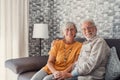 Beautiful hoary good-looking mature spouses relaxing together on comfy couch at modern home smiling staring at camera feel Royalty Free Stock Photo
