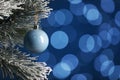 Beautiful holiday bauble hanging on Christmas tree against blue background with blurred festive lights Royalty Free Stock Photo