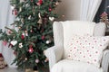 Beautiful holiday decorated room with Christmas tree and white comfortable chair
