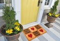 Beautiful Home sweet home peach color coir doormat with hearts Placed outside door with yellow flowers and green leaves Royalty Free Stock Photo