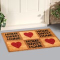 Beautiful Home sweet home peach color coir doormat with hearts Placed outside door with yellow flowers and green leaves Royalty Free Stock Photo