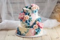 A beautiful home wedding three-tiered cake decorated with pink roses and blue flowers in a rustic style on wooden table Royalty Free Stock Photo