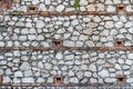 A beautiful texture of an old wall from gray stones and orange brick with green plants and brown ivy branches Royalty Free Stock Photo