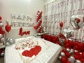 Romantic honeymoon bedroom decoration with a couple of swans kissing made from towels, balloons, and rose petals Royalty Free Stock Photo