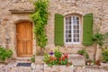 A beautiful house facade in Provence, with a wooden door and French window with green shutters. Royalty Free Stock Photo