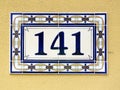 Beautiful house sign "141" against a yellow wall