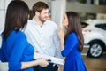 Young married couple buying their first car together in auto salon