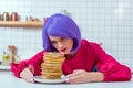 beautiful housewife with purple hair looking at plate with pancakes Royalty Free Stock Photo