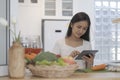 Beautiful housewife standing at kitchen counter and reading online recipe for making healthy meal. Dieting, healthy lifestyle Royalty Free Stock Photo