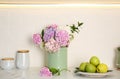 Beautiful hydrangea flowers and apples on countertop