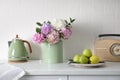 Beautiful hydrangea flowers, kettle and apples on countertop