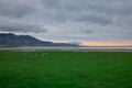 Beautiful icelandic landscape in early morning. Green grass, yellow sunrise, clouds and road in the distance. Very beautiful Royalty Free Stock Photo