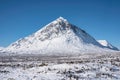 Beautiful iconic landscape Winter image of Stob Dearg Buachaille Etive Mor mountain in Scottish Highlands againstd vibrant blue