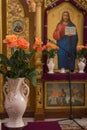 Beautiful icons with roses in flower pots. Religious images in christian cathedral. Religious art. Christian church interior.