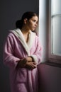 Beautiful ill sad girl in pajamas looking through hospital window Royalty Free Stock Photo