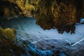 Beautiful illuminated limestone stalactites in Adygeya cave, underground river with reflection of blue light
