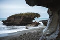 Beautiful image of a beach with a rock formation in the middle taken on a cloudy winter day at Truman Track, New Zealand