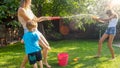 Beautiful image of happy laughing family with children having fun at hot summer day with water guns and garden hose Royalty Free Stock Photo